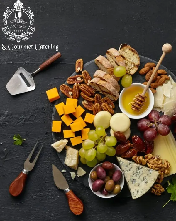 A classic charcuterie and cheese board, beautifully styled on a dark slate platter. It features a mix of hard and soft cheeses, nuts, dates, and honey, perfect for any gathering.