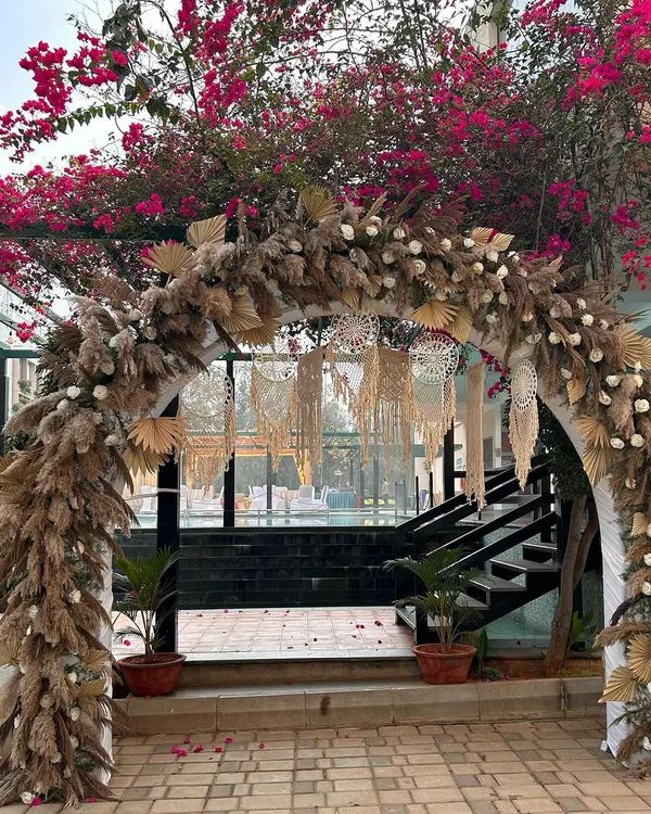 A beautiful boho-chic entrance arch. We used an abundance of dried pampas grass, palm leaves, and macrame hangings to create a dreamy, textured welcome for guests.