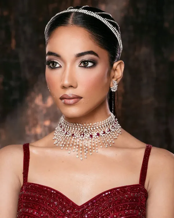 A classic beauty portrait. The focus is on the luminous skin, sharp winged eyeliner, and the sparkle of the ruby and diamond choker.