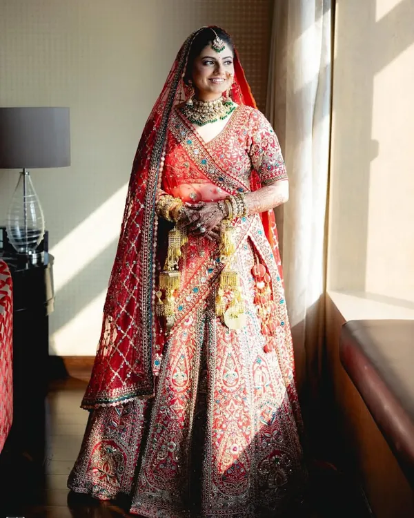A full view of a classic red bridal lehenga, rich with embroidery. I help you achieve this iconic wedding look with my premium rental collection.