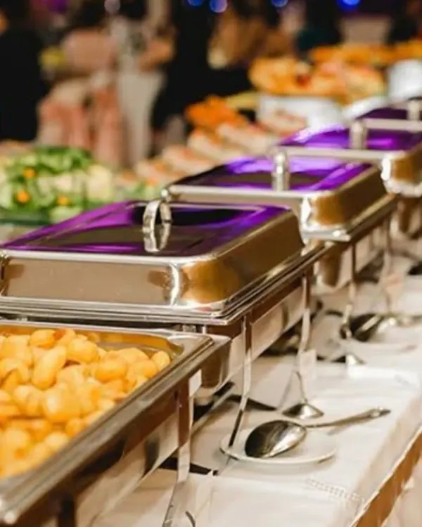A close-up of a professionally arranged buffet line. I ensure the catering setup is clean, elegant, and inviting, with a variety of dishes served in high-quality chafing dishes to keep the food warm and fresh.