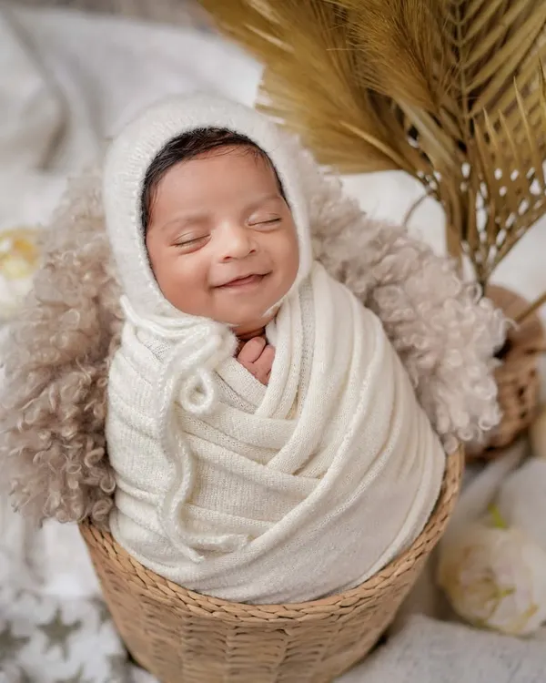 A smile that warms the heart. I love this boho-inspired setup, using a wicker basket, a soft knitted bonnet, and dried palms for a natural, earthy feel.