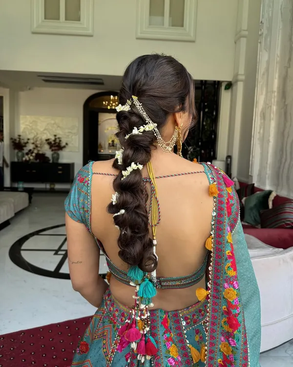 A braided beauty adorned with fresh mogras and colorful tassels. This is a perfect example of a fun yet traditional Mehendi hairstyle.