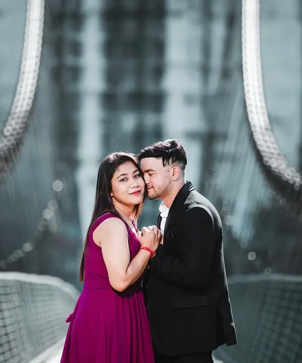 A romantic and moody shot on a suspension bridge. The cool color tones and the couple's close embrace create a very cinematic and intimate feel.