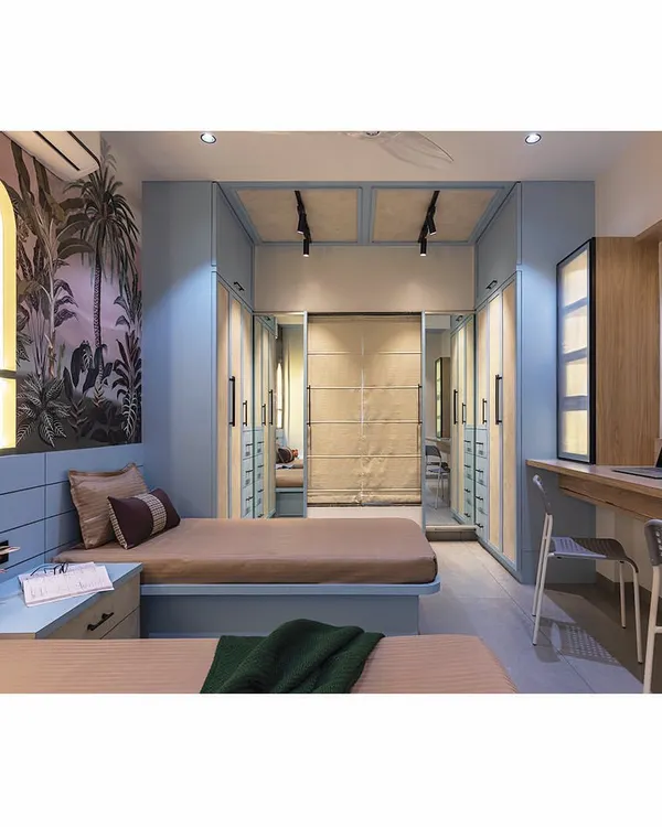 A dream room for teenage siblings. We used a sophisticated tropical wallpaper and a cool blue color palette to create a space that feels both youthful and grown-up. The design includes twin beds and a central shared study area.