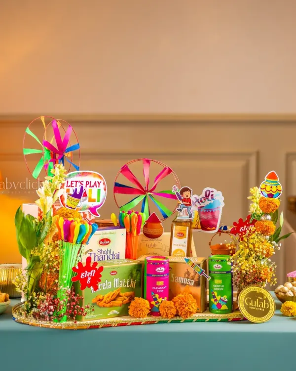 A vibrant Holi festival hamper from Gulab Sweets, filled with snacks, colors, and festive props, creating a joyful and celebratory mood.