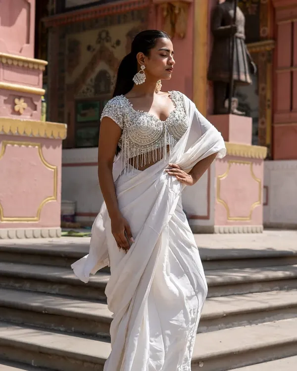 Presenting the Ivory Edit. This stunning look features a heavily beaded blouse with tassels paired with a simple white drape saree.