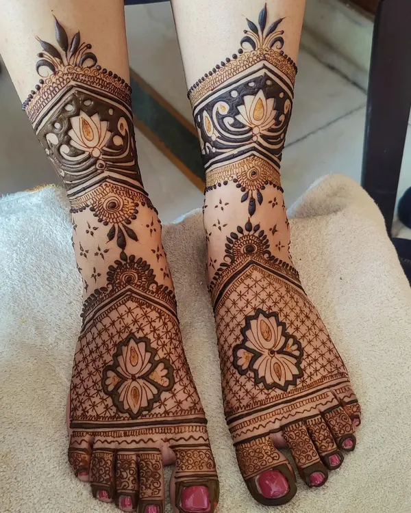 A stunning and clean bridal foot mehandi design. The combination of lotus figures with intricate net patterns creates a very elegant and traditional look.