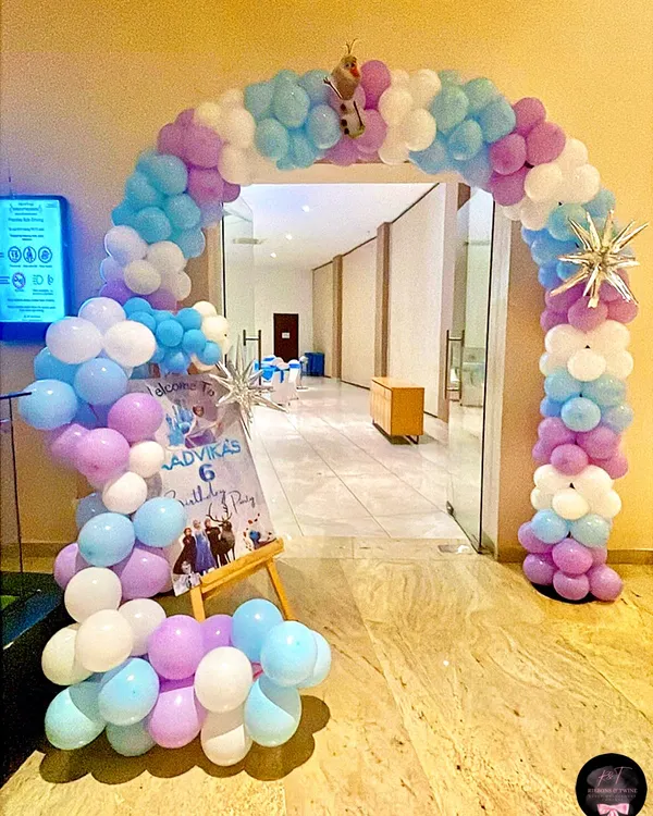 A grand entrance for a Frozen-themed party, featuring a full balloon arch in pastel blue, purple, and white. I added snowflake accents and a small Olaf cutout to welcome guests into the winter wonderland.