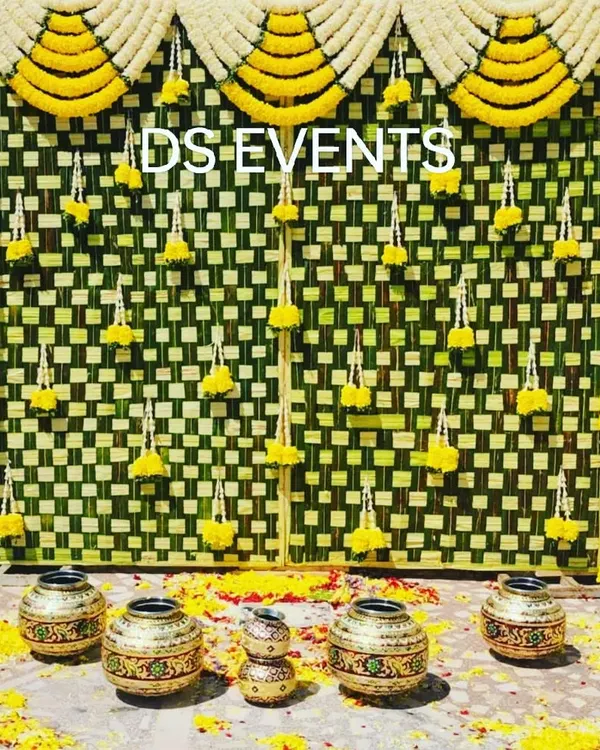 An eco-friendly backdrop crafted from intricately woven coconut leaves (thenga olai). The hanging marigold and tuberose garlands add a touch of color and fragrance, perfect for a traditional pooja or ceremony.