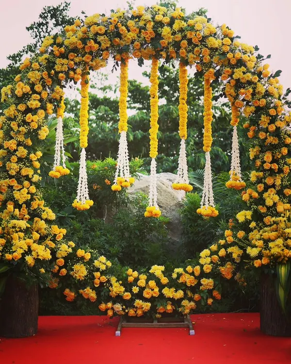 A beautiful circular floral arch made of yellow marigolds, perfect for a Haldi ceremony. The hanging floral strings add a traditional and elegant touch to the decor.