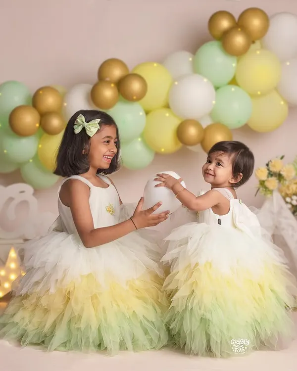 A playful moment between two sisters in matching ombre tulle dresses. Capturing these moments of sharing and fun is what sibling photoshoots are all about.