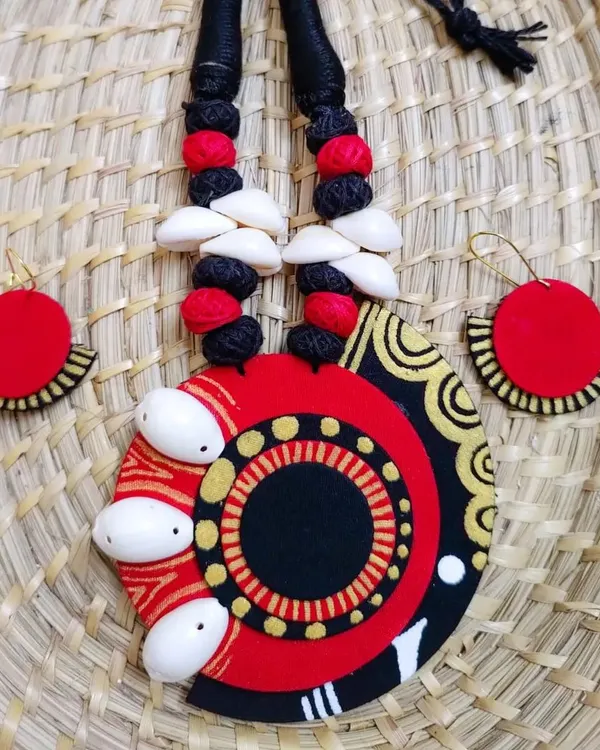 This statement necklace set is a perfect example of my craft. It combines hand-painted fabric in bold red and black with intricate patterns and is embellished with natural cowrie shells for a distinct tribal-boho feel. The matching earrings complete this lightweight, wearable art piece.
