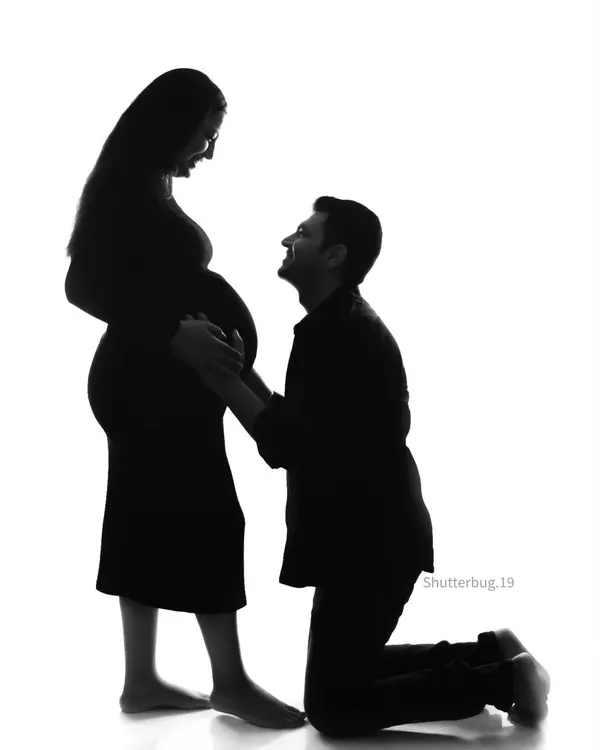 A timeless silhouette capturing a tender moment between expecting parents. The high-contrast black and white style emphasizes the beautiful shape of the baby bump and the emotional connection in this couple's maternity portrait.
