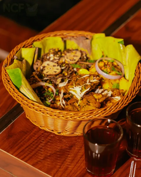 A Manipuri relish munch basket, featuring a mix of Singju, Bora, Kelichana, and Aloo mixture, served with red tea (Cha-ngang).