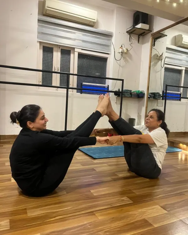 Partner yoga is a beautiful way to connect. Here, two students practice a partner boat pose (Navasana), relying on each other for balance and support.