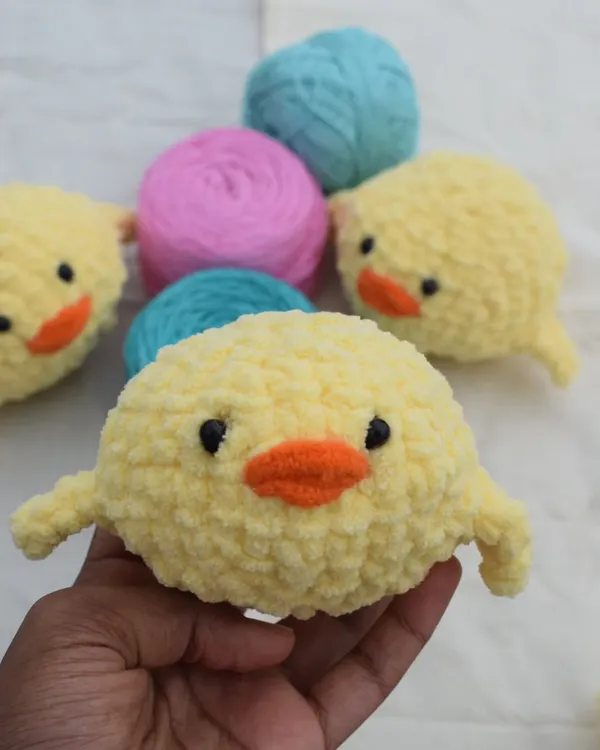 A handful of fluffy joy! This is one of my plush chick designs, held up against the yarn I use to show the raw material before it becomes a cute friend.
