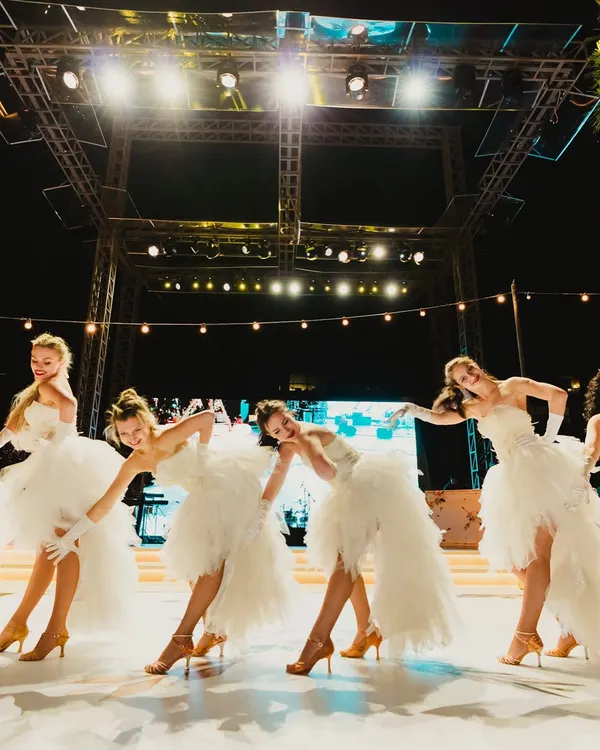 A troupe of dancers in elegant white tulle dresses, performing a choreographed routine. We work with top dance groups to add grace and energy to our events.