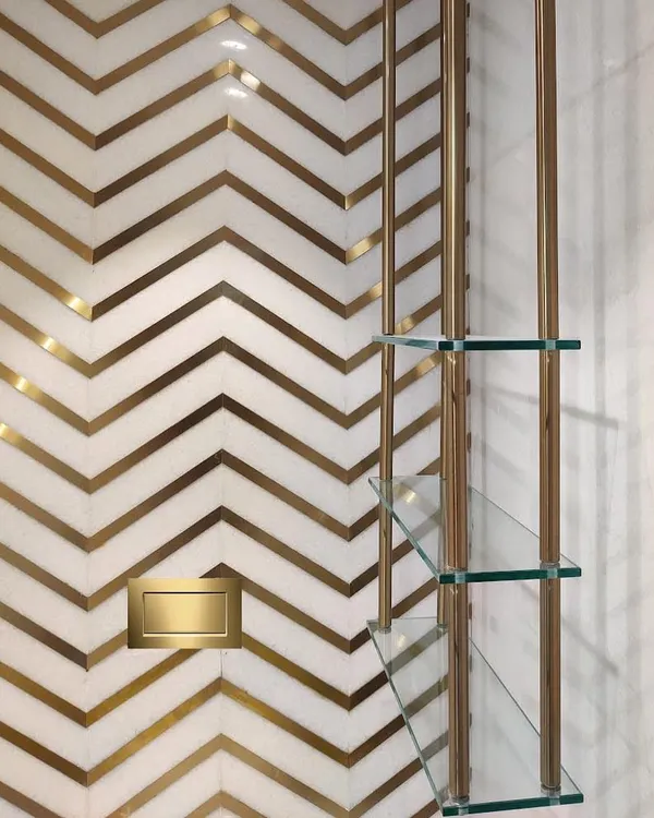 A detail shot from a luxury powder room I designed. The combination of white marble with a custom brass inlay in a chevron pattern creates a dramatic and sophisticated feature wall.