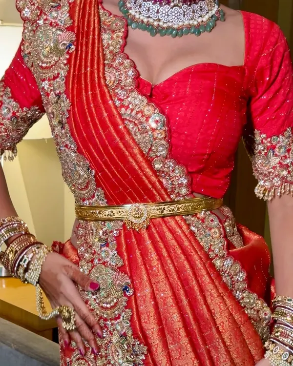 A close-up of a unique red bridal drape. This fusion style combines the look of a lehenga with the elegance of a saree, creating a modern and striking silhouette.