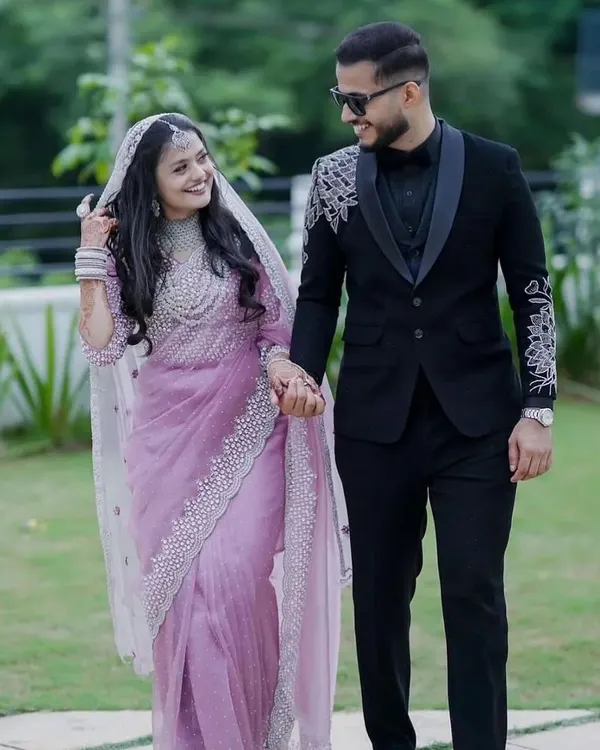 A happy couple on their wedding day. We tailored this groom's custom black tuxedo, which features detailed silver embroidery on the shoulders and a classic satin shawl lapel. It's a perfect example of a modern reception outfit.