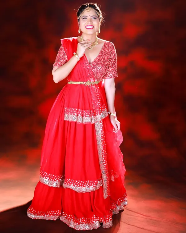 A vibrant, full-length portrait of a model in a stunning red lehenga. I used a textured red backdrop and specific lighting to create a rich, monochromatic look that makes the silver details pop.