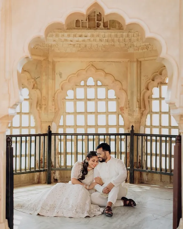 A quiet moment of togetherness captured within the intricate arches of Amer Fort. We use architectural framing and soft, natural light to create timeless, romantic portraits that feel like a scene from a classic film.
