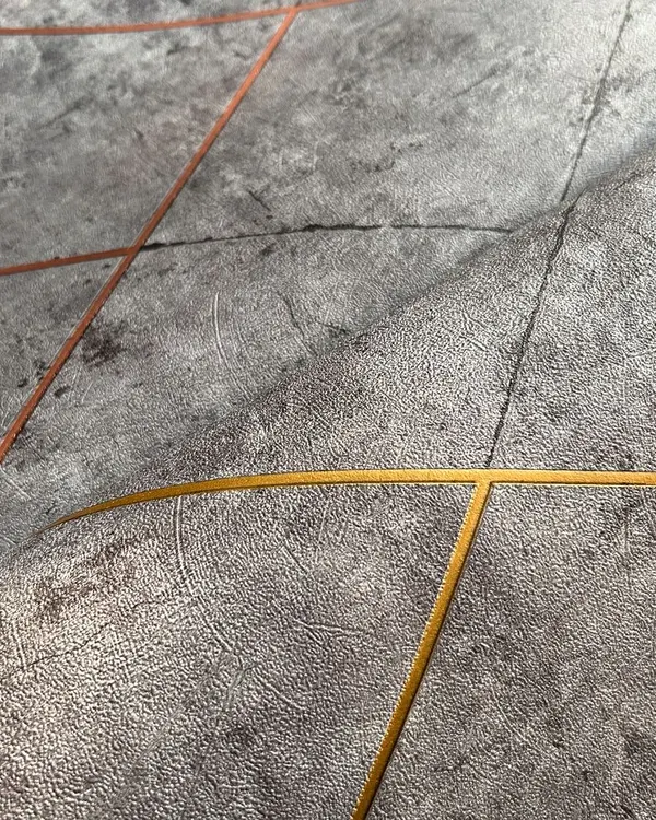 This modern geometric wallpaper features a textured grey background with intersecting lines in copper and gold. It's a luxurious design that adds a touch of contemporary elegance to any space.