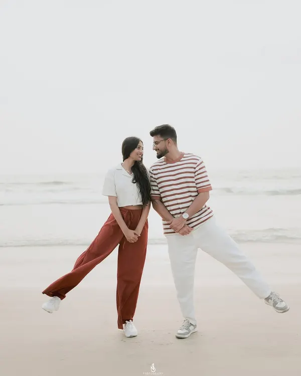 A fun, playful pose on the sands of a quiet beach. Coordinated casual outfits are a great choice for a relaxed and comfortable beach photoshoot.