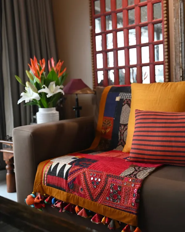 This scrap quilt, seen here on a sofa, is a celebration of asymmetry and spontaneity. It features a mix of machine and Boro-style hand stitching, with a vintage Kutch embroidery patch anchoring the composition.