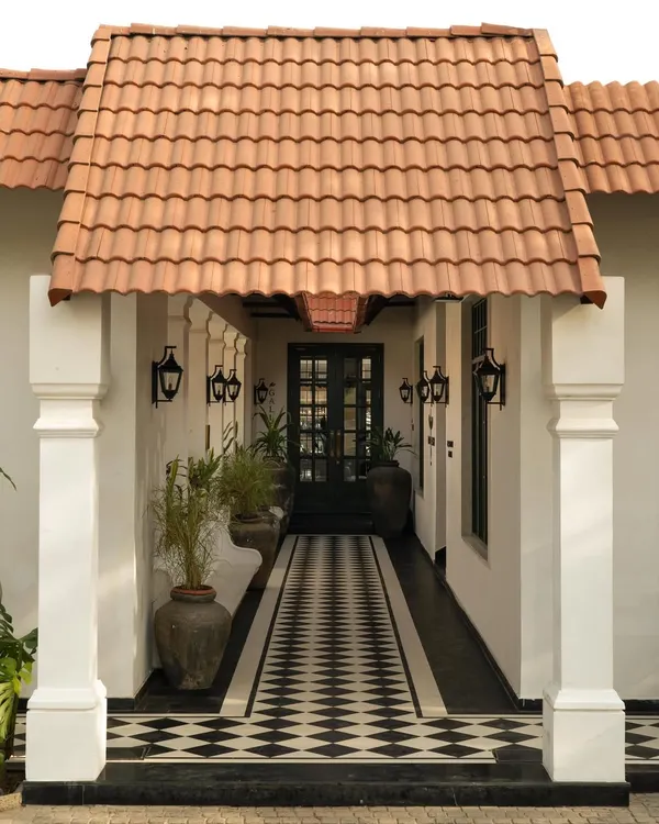 The entrance to Elgin Cafe in Ludhiana, where a calibrated dialogue between colonial typology and contemporary clarity begins. The checkerboard path guides the eye, framed by classical columns and a terracotta roof.