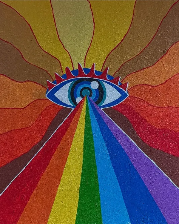 A close-up of a psychedelic eye mural, where a rainbow of light radiates from the center. The warm colour palette and bold lines create a mesmerizing effect.