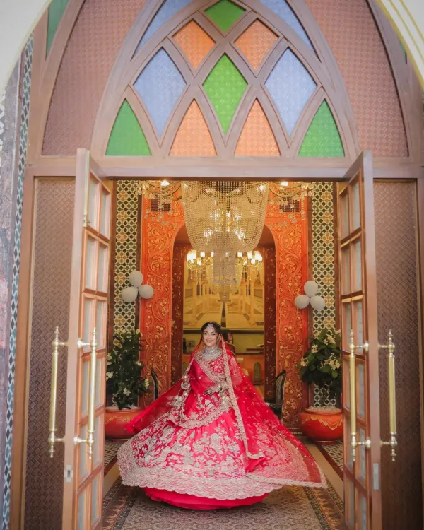 A grand bridal entry shot of Devanshi. The wide angle captures her magnificent lehenga and the opulent decor of the venue as she makes her way to her forever. This is a true statement bridal portrait.