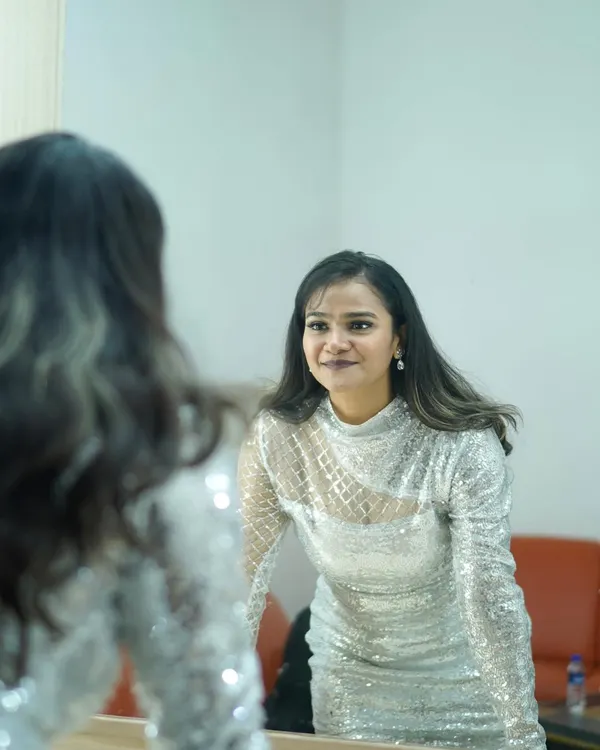 A behind-the-scenes moment, getting ready in a silver sequin dress. The mirror reflection adds depth and a sense of anticipation.