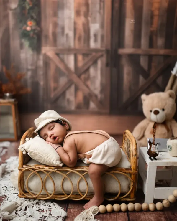 A little boy in a newsboy cap, sleeping peacefully on a miniature rattan bed. This rustic setup is full of charming, old-world details.
