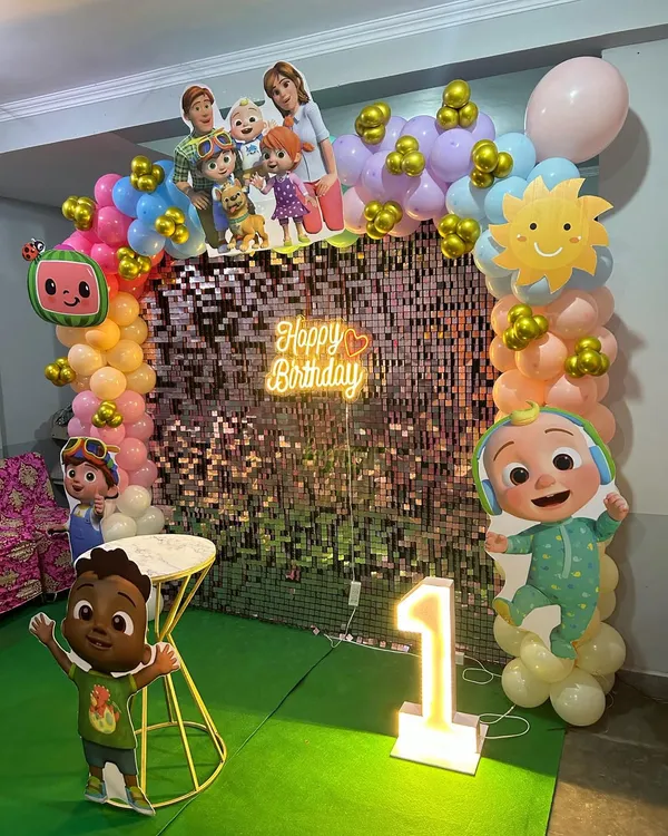 Our Cocomelon theme is a huge hit with toddlers. This setup includes a colorful balloon arch, character cutouts, a shimmer backdrop, and a light-up number '1' for a memorable first birthday.