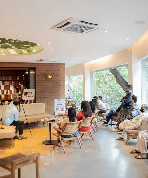 A wide shot of the audience at Stuti Changle's book launch, showing a full house of attentive readers in a cozy cafe setting.