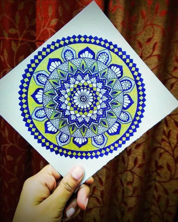 Here I am holding a finished mandala that uses a cool color palette of blue and green. It's amazing how colors can completely change the feeling of a design.