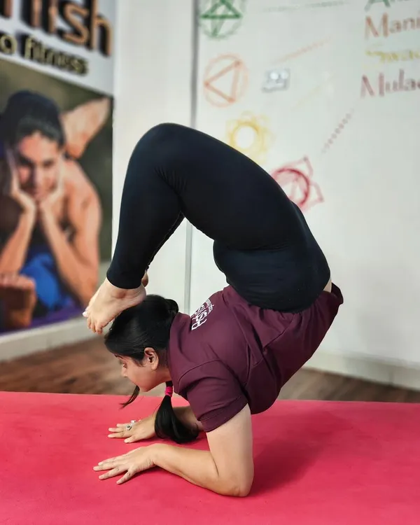 A student demonstrates incredible strength and flexibility in Vrischikasana (Scorpion Pose) on their forearms. This pose is a pinnacle of our advanced asana training, combining an inversion with a deep backbend.