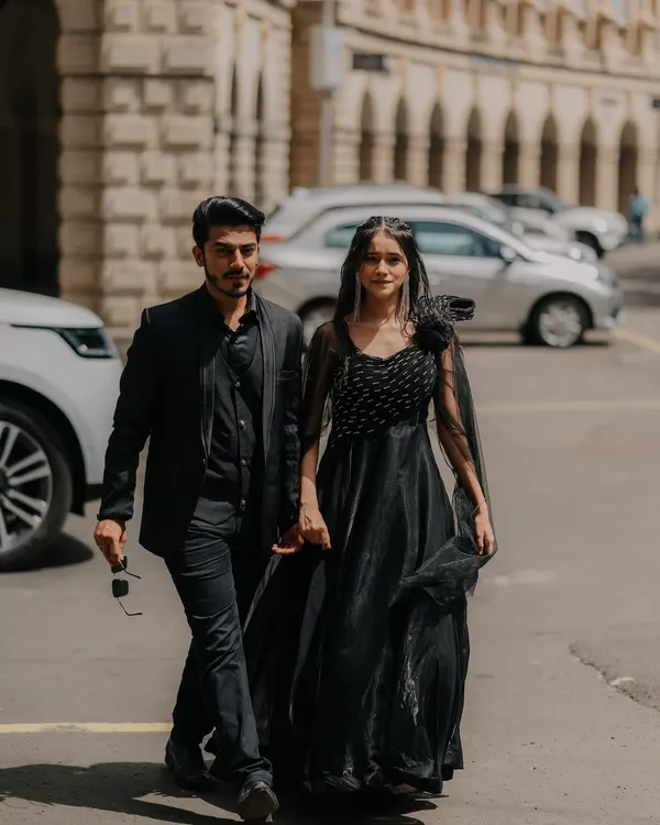 A candid, on-the-move shot of the couple walking through the streets of Mumbai. Their coordinated black outfits and confident stride give this pre-wedding photo a cool, cinematic vibe.