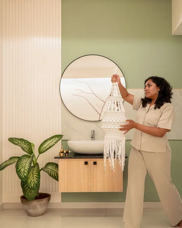 This wash basin area is a focal nook that connects the entire house. We used a pastel green on the wall to add a subtle pop of color, while the fluted panel adds texture. The round mirror and simple wooden cabinet hide the plumbing and complete this unique, understated space.