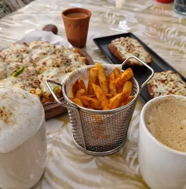 A perfect meal spread at My Baagaan. Cheesy pizza, crispy peri-peri fries, garlic bread, and frothy cappuccinos. It's comfort food at its best, enjoyed in the best atmosphere.
