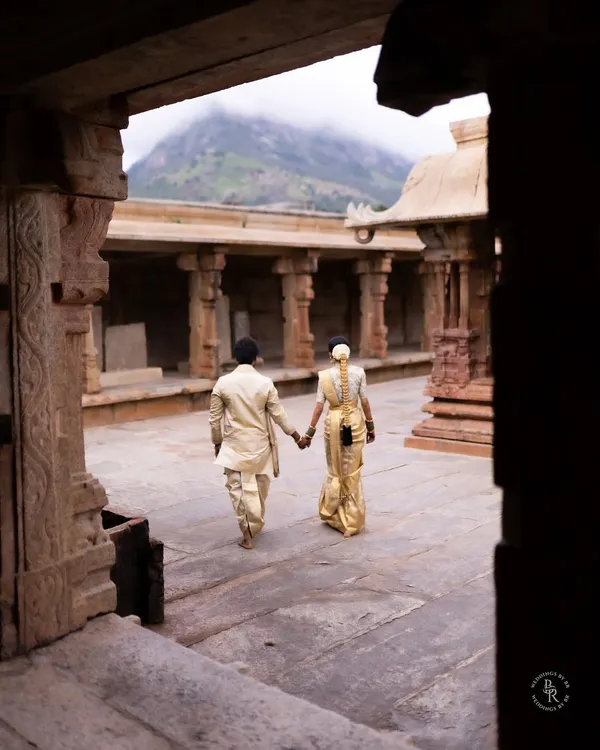 Walking hand-in-hand through the stone corridors of a historic temple, with the mountains in the distance. This frame captures the beginning of their journey together, rooted in tradition.