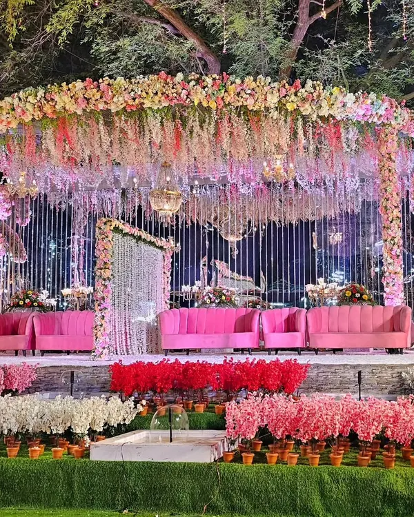 A full view of the extravagant floral stage, showing how the elevated platform and lush foreground arrangements create a multi-layered, immersive setting. This design is perfect for large outdoor venues like Lokhandwala Garden.
