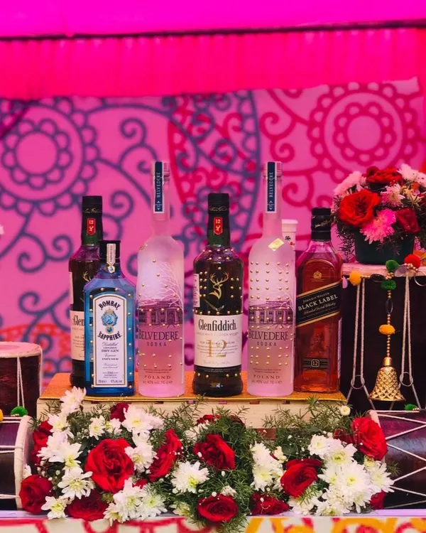 The centerpiece of my 'Funjabi' themed bar. Premium liquor bottles are artfully arranged on a bed of flowers, flanked by two traditional dhols, perfectly capturing the celebratory spirit of a Punjabi wedding.