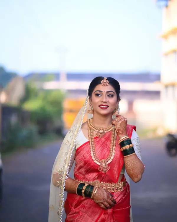 A beautiful shot of bride Bhoomika in her custom wedding attire. The contrast of the intricately embroidered white blouse against the rich red silk saree creates a timeless and elegant bridal look.