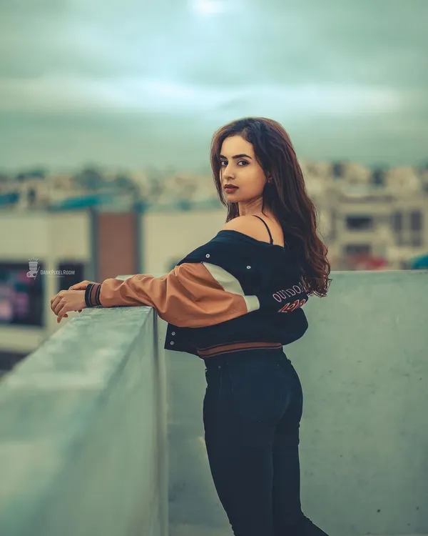 A classic rooftop portrait with a moody, cinematic edit. The city skyline and overcast sky create a dramatic backdrop that emphasizes the subject's presence.