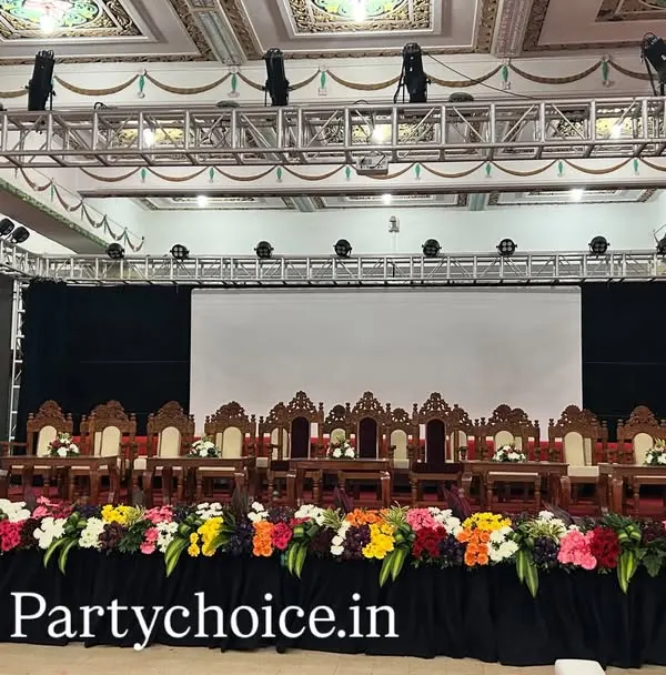 We design and execute large-scale stage setups for high-profile government and corporate events. This setup for a DCM meeting includes a multi-seat dais for dignitaries, dual lecterns, professional lighting on a truss system, and a full-length floral runner.