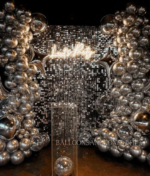 This is the definition of a party backdrop. A silver sequin wall, chrome balloon garlands, star-shaped foil balloons, and disco balls come together for a high-energy, disco-glam vibe.