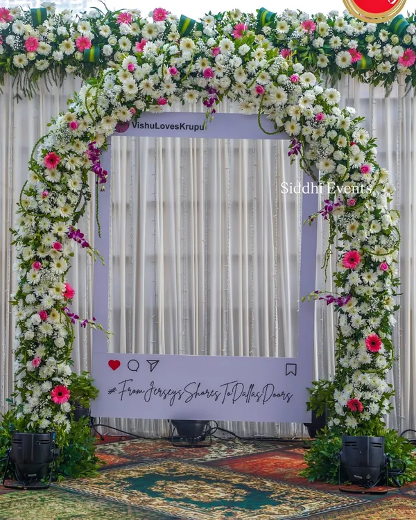 We create fun, interactive photo opportunities like this custom Instagram frame, adorned with a lush arch of white and pink flowers, personalized with the couple's handle and hashtag.